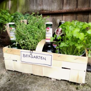 Spankorb mit Bierflaschen und Kräutern auf einem Stein; Schild mit der Schrift Biergarten drangeheftet; HofladenBOX